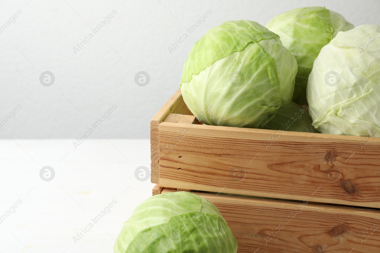 Photo of White cabbage in crate on table, closeup. Space for text