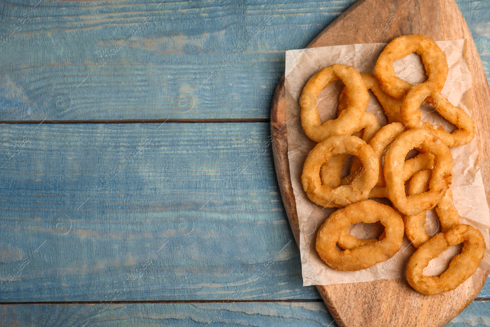 Photo of Fried onion rings served on blue wooden table, top view. Space for text