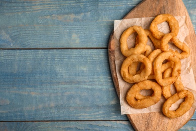 Photo of Fried onion rings served on blue wooden table, top view. Space for text
