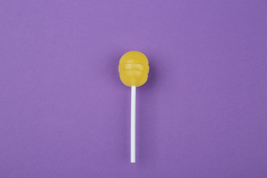 Photo of Tasty lemon lollipop on purple background, top view