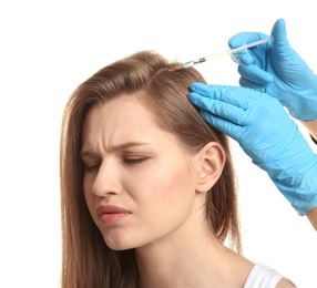 Young woman with hair loss problem receiving injection on white background