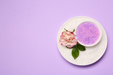 Photo of Aromatic sea salt and beautiful flower on purple background, top view. Space for text