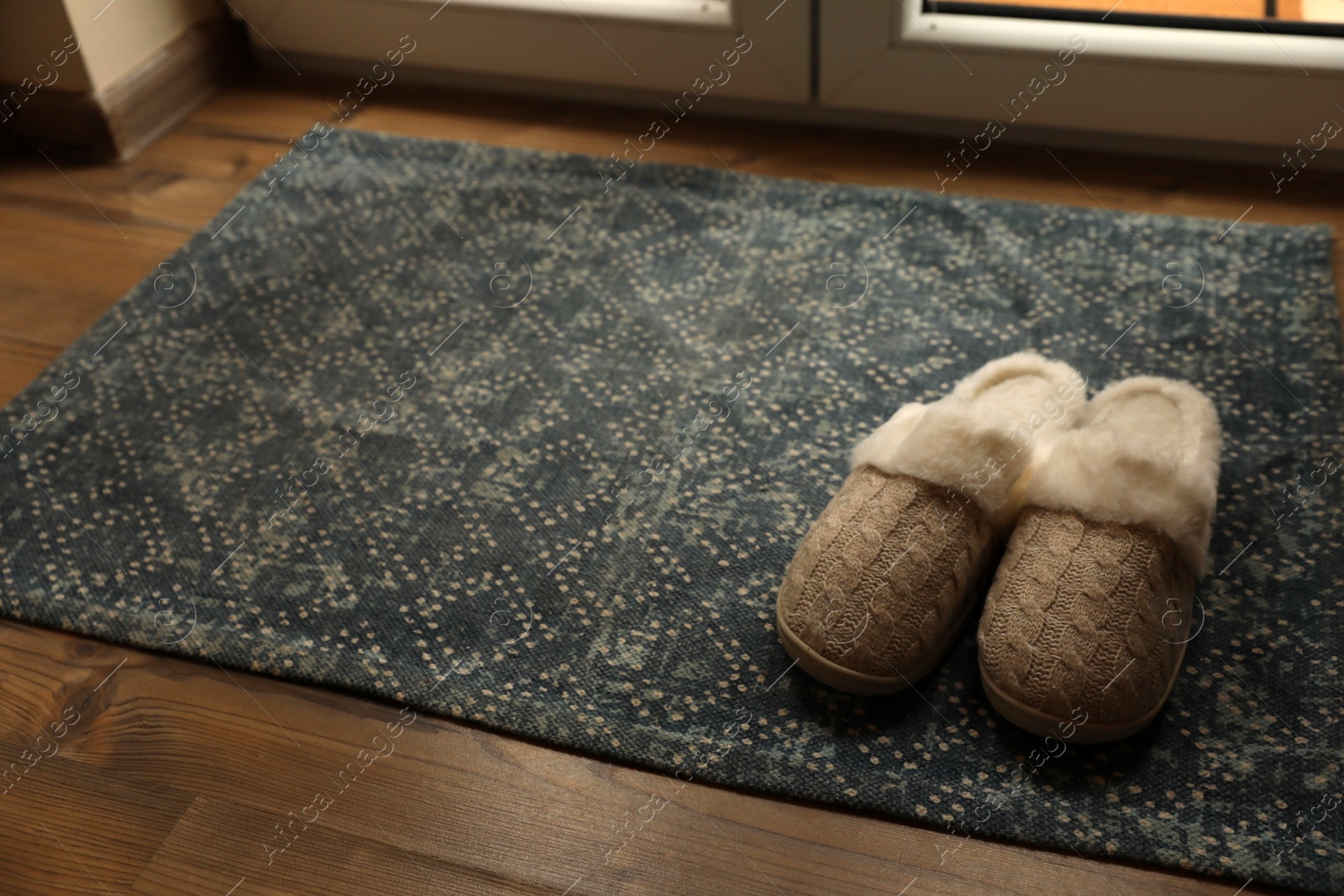 Photo of Stylish door mat and slippers on wooden floor indoors