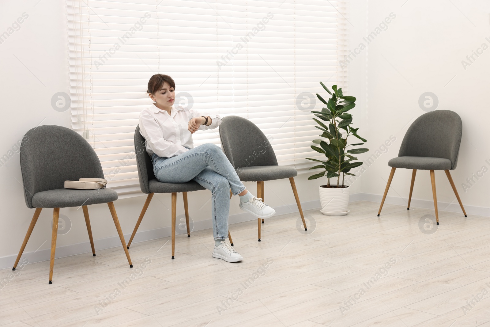 Photo of Woman sitting on chair and waiting for appointment indoors