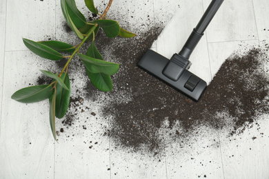 Photo of Removing soil from wooden floor with vacuum cleaner at home, top view