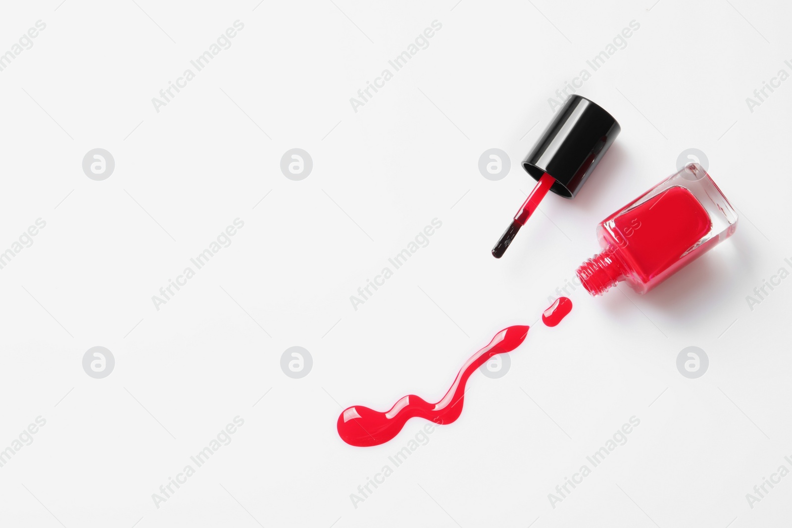 Photo of Spilled color nail polish with bottle and brush on white background, top view