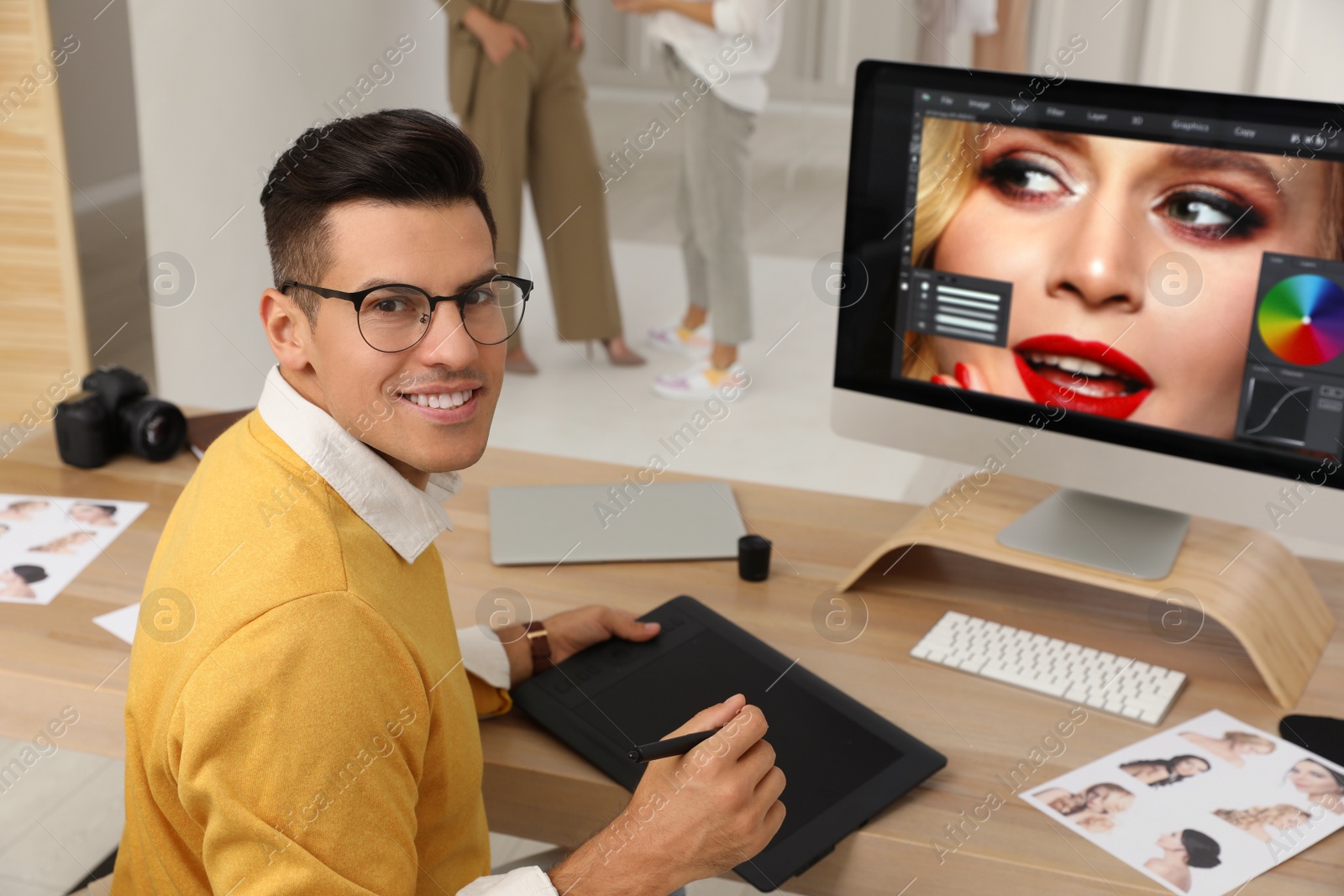 Photo of Professional retoucher working with graphic tablet at desk in photo studio