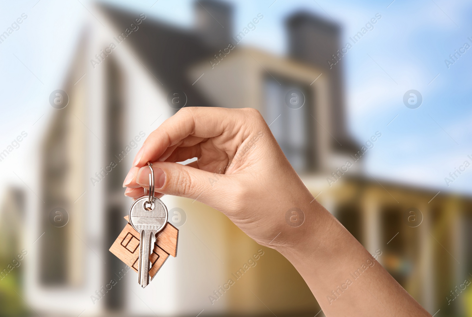 Image of Woman with key near new modern house outdoors, closeup