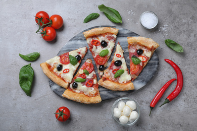 Pieces of delicious pizza Diablo on grey table, flat lay