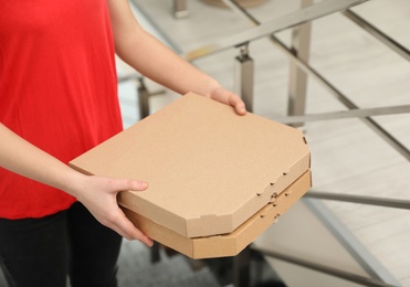 Female courier with pizza boxes indoors, closeup. Food delivery service