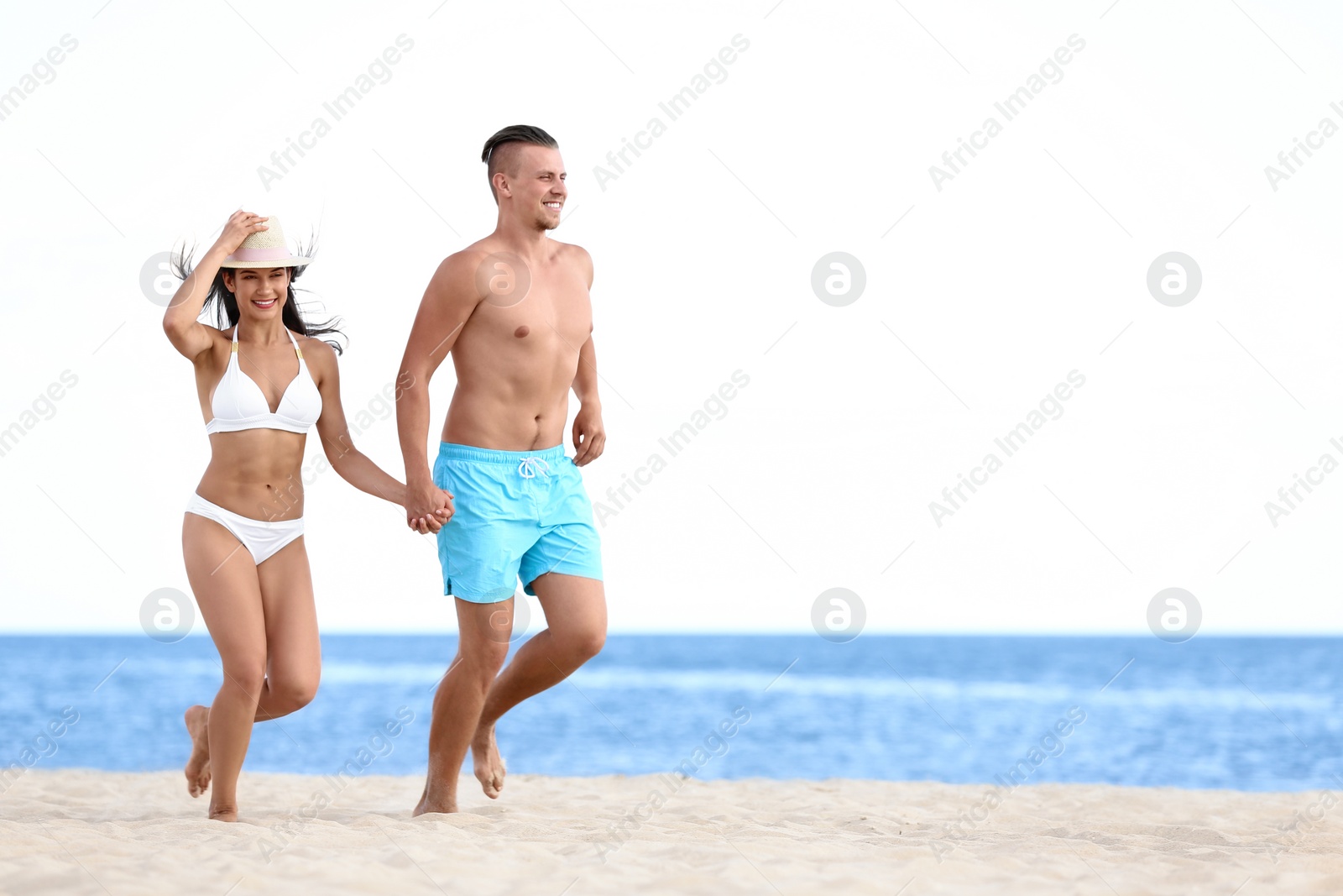 Photo of Young woman in bikini spending time with her boyfriend on beach. Lovely couple