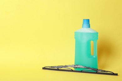 Photo of Bottle of windshield washer fluid and wiper on yellow background. Space for text