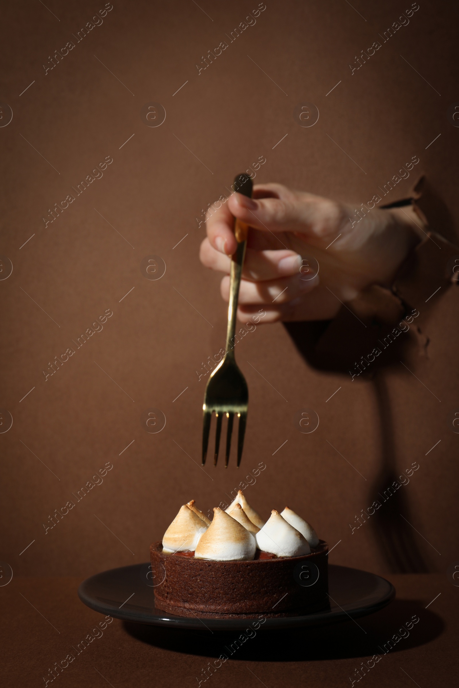 Photo of Woman tearing brown paper willing to eat delicious tart, closeup