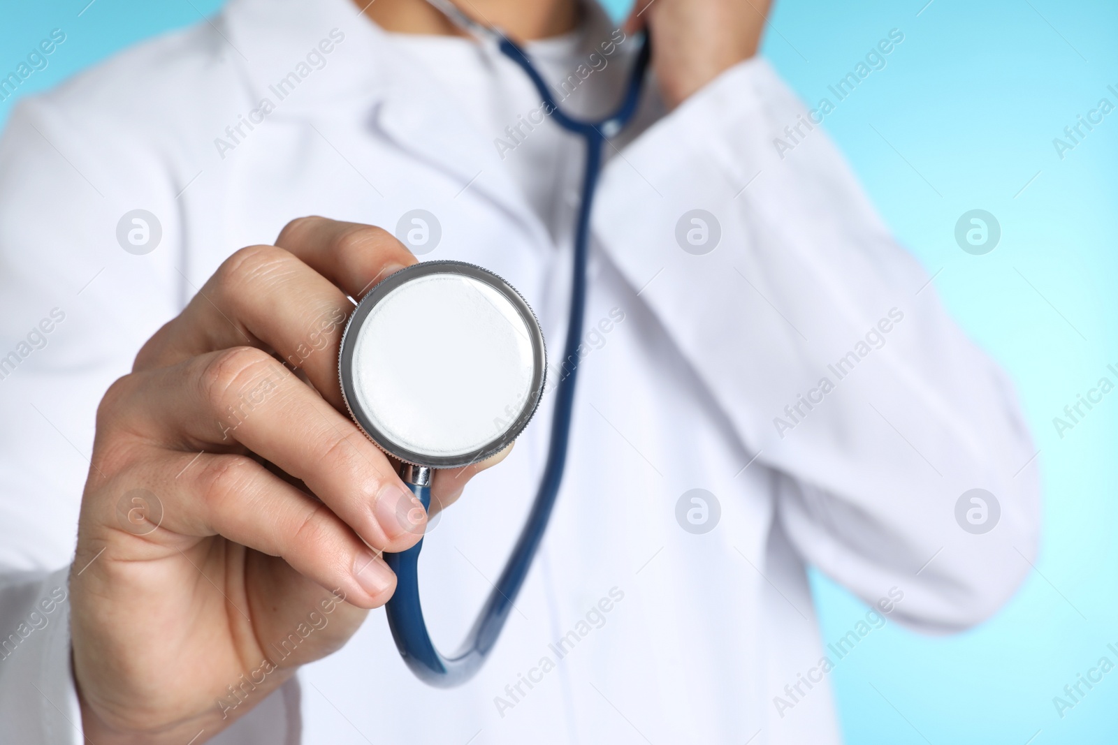 Photo of Male doctor with stethoscope on color background, closeup. Medical object