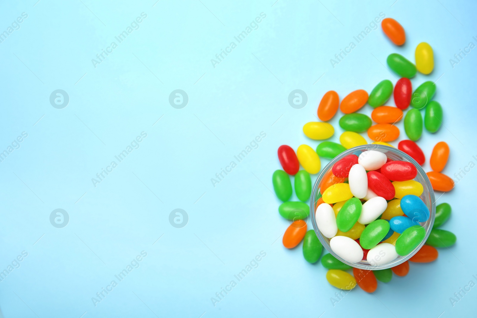 Photo of Flat lay composition with bowl of jelly beans on color background. Space for text