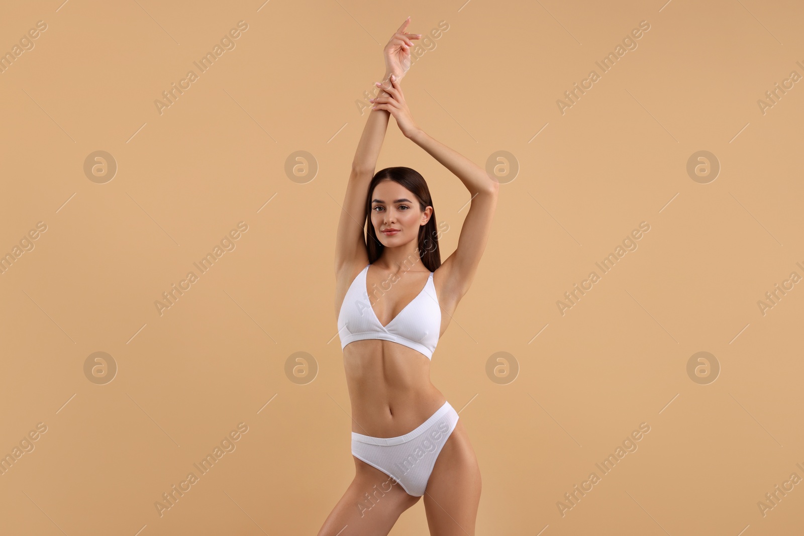 Photo of Young woman in stylish white bikini on beige background