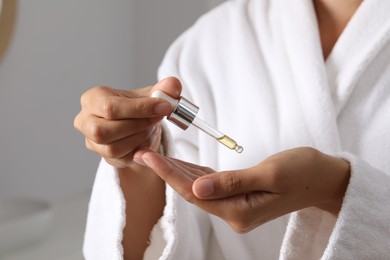Photo of Woman applying cosmetic serum onto her hand on grey background, closeup
