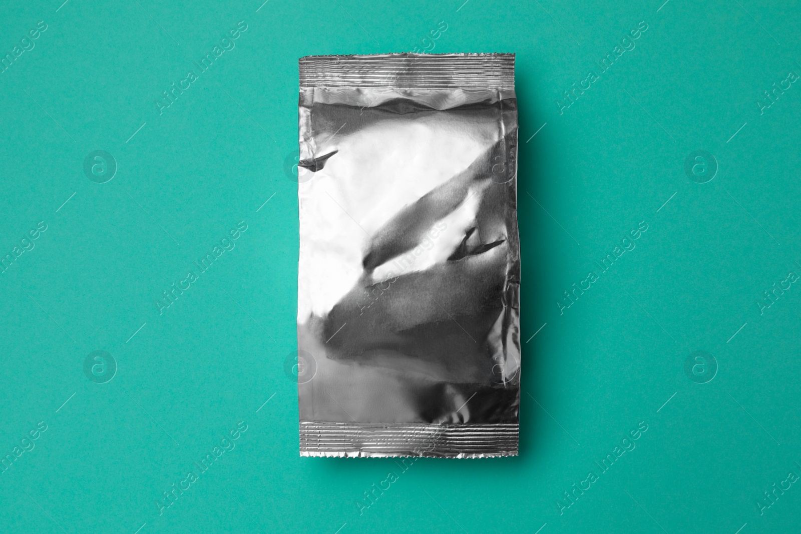 Photo of Blank foil package on turquoise background, top view