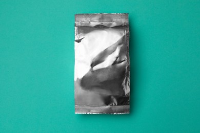 Photo of Blank foil package on turquoise background, top view