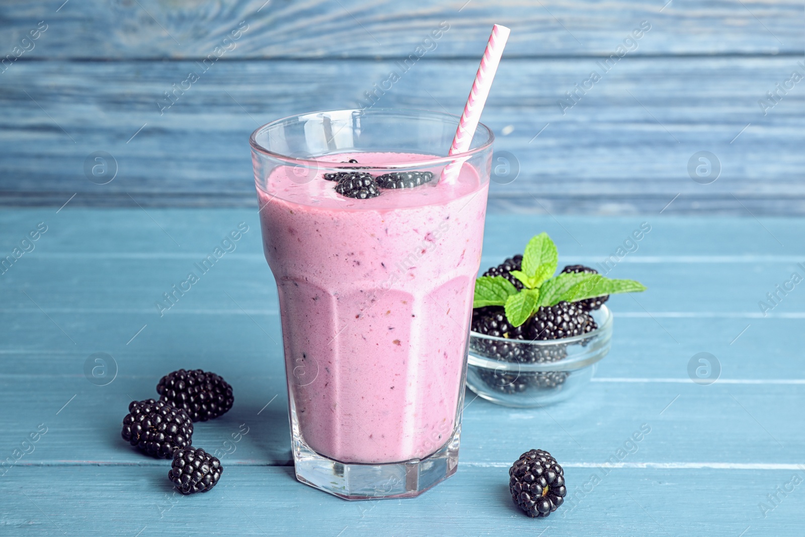Photo of Delicious blackberry smoothie in glass on blue wooden table