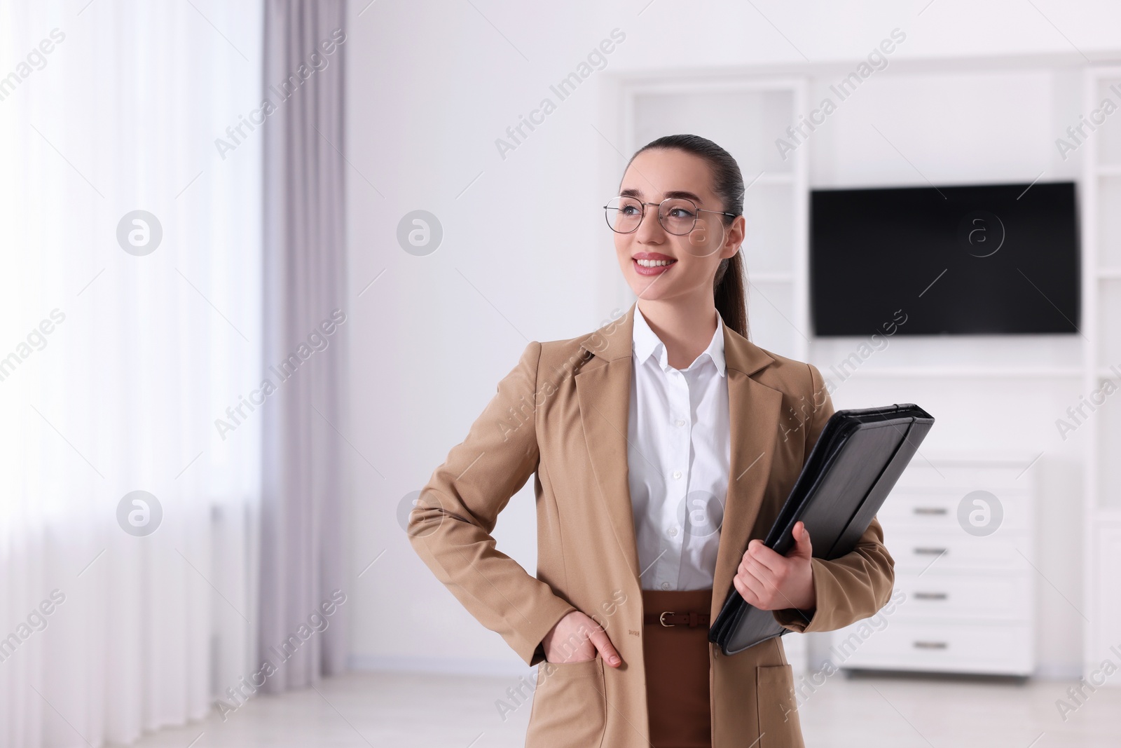 Photo of Happy real estate agent with leather portfolio indoors. Space for text