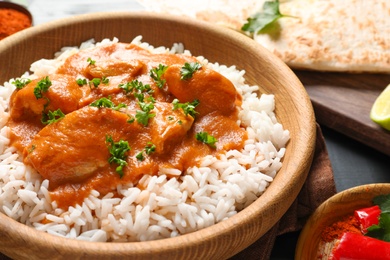 Photo of Bowl of butter chicken with rice on table