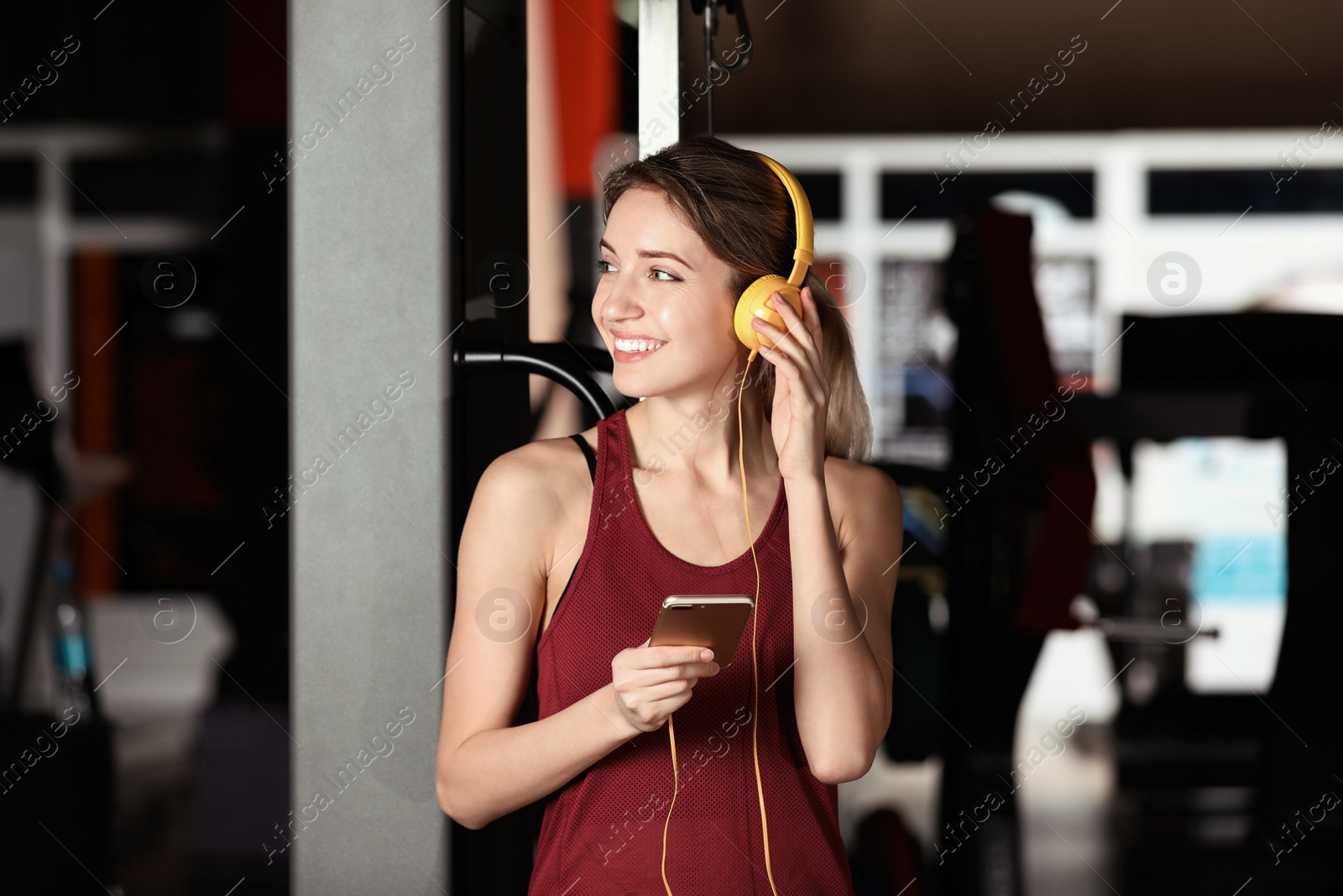 Photo of Young woman with headphones listening to music on mobile device at gym