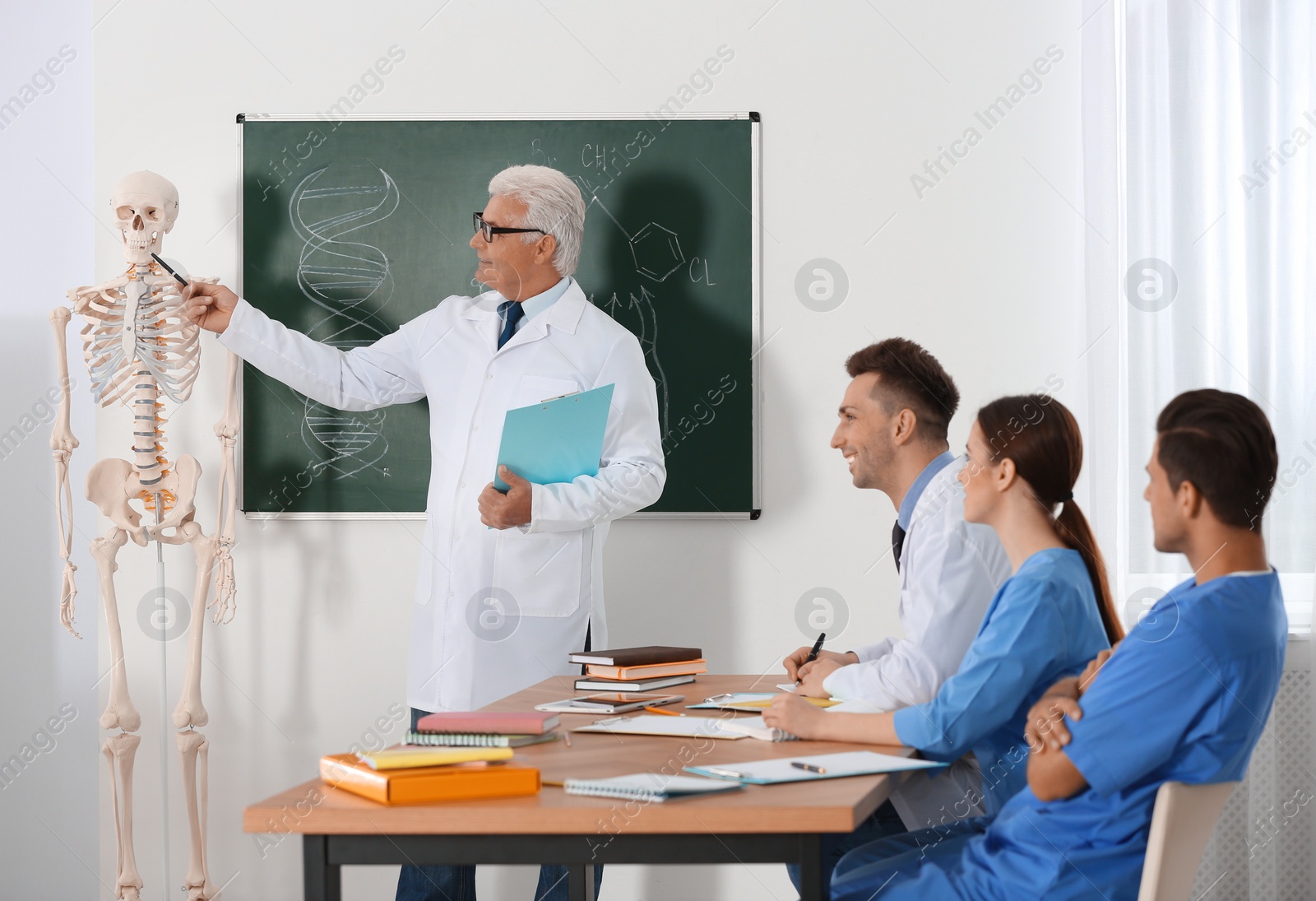 Photo of Medical students and professor studying human skeleton anatomy in classroom