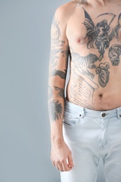 Photo of Young man with stylish tattoos on grey background