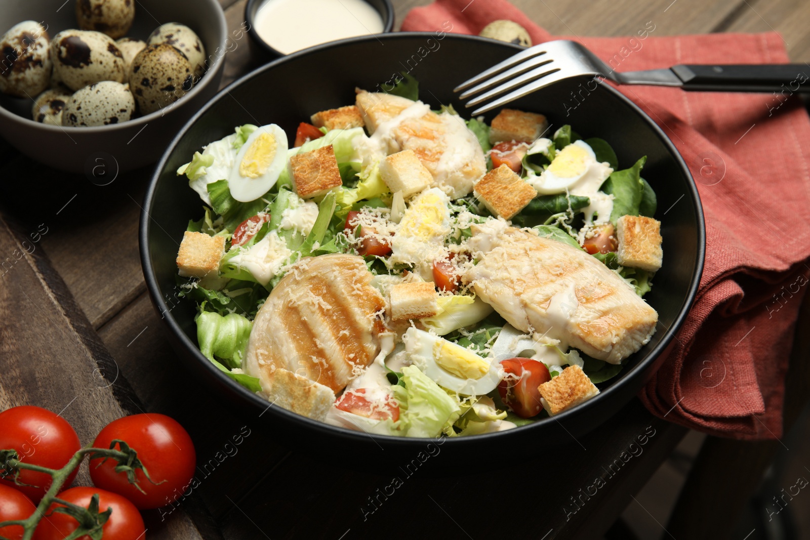 Photo of Delicious Caesar salad in bowl on wooden table