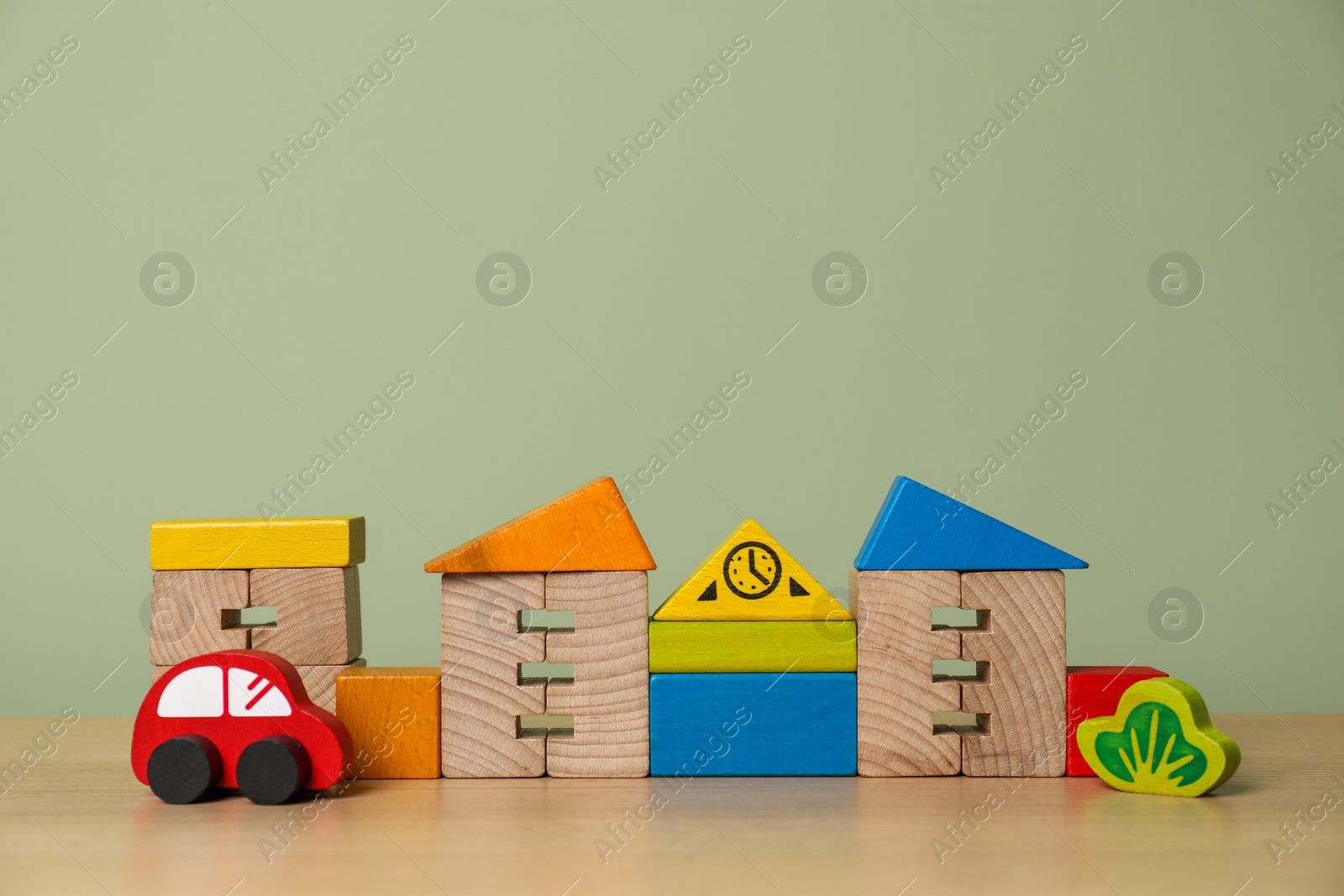 Photo of Set of different wooden toys on table near olive wall, space for text. Children's development