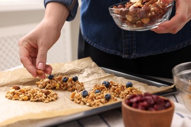 Making granola bars. Woman with nuts at table in kitchen, closeup