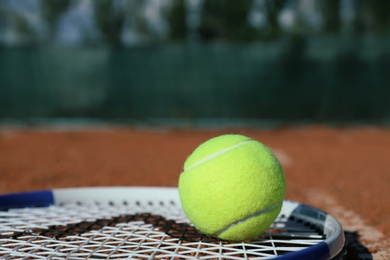 Photo of Tennis ball and racket on clay court, closeup. Space for text