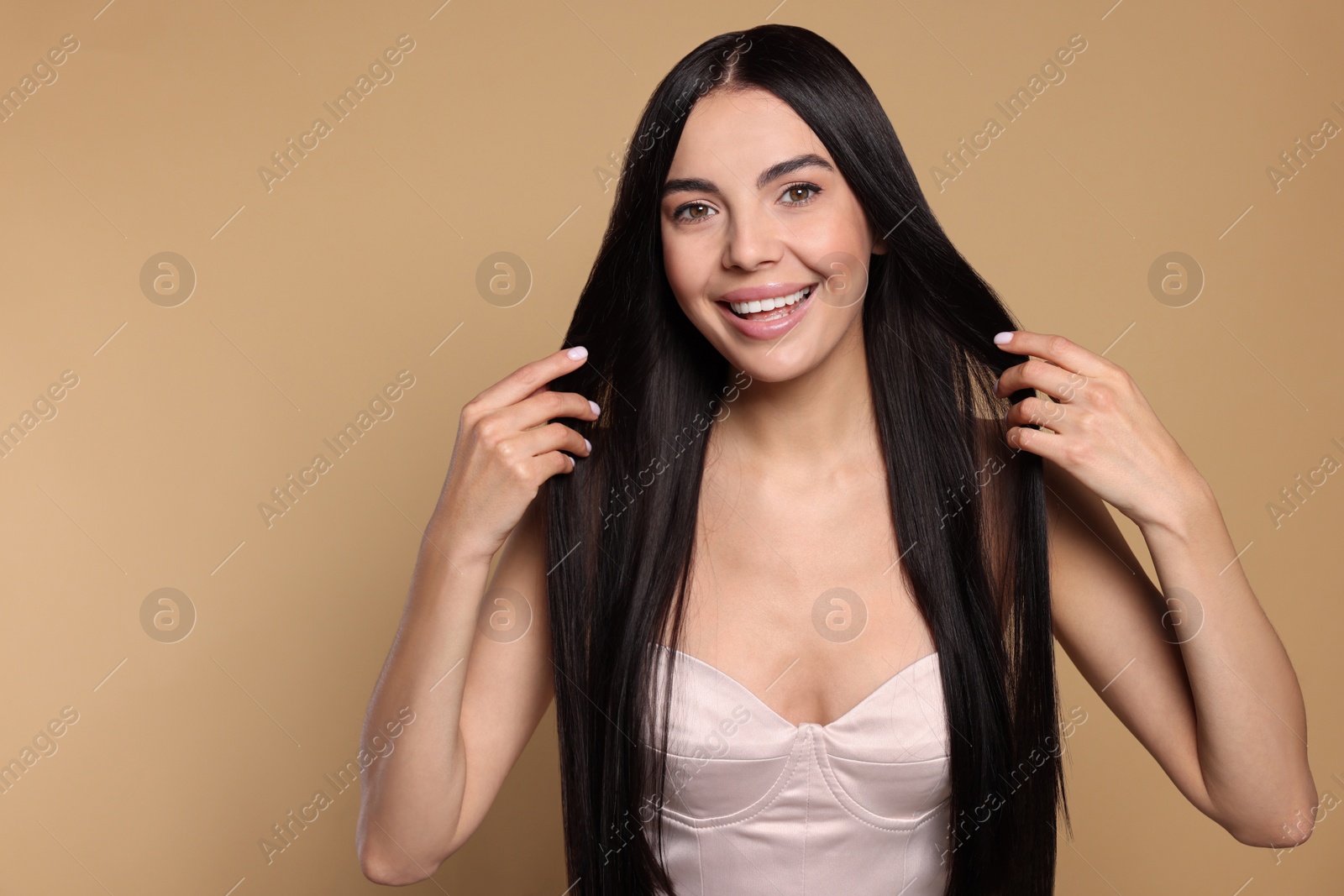 Photo of Portrait of beautiful young woman with healthy strong hair on beige background, space for text