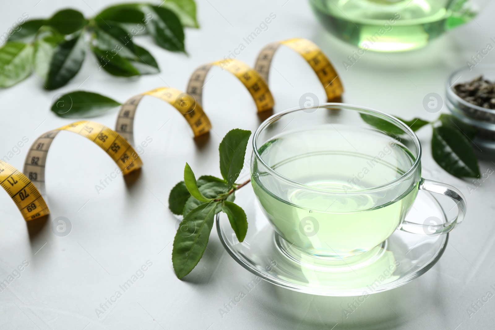 Photo of Cup of herbal diet tea and measuring tape on light table