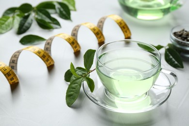 Cup of herbal diet tea and measuring tape on light table