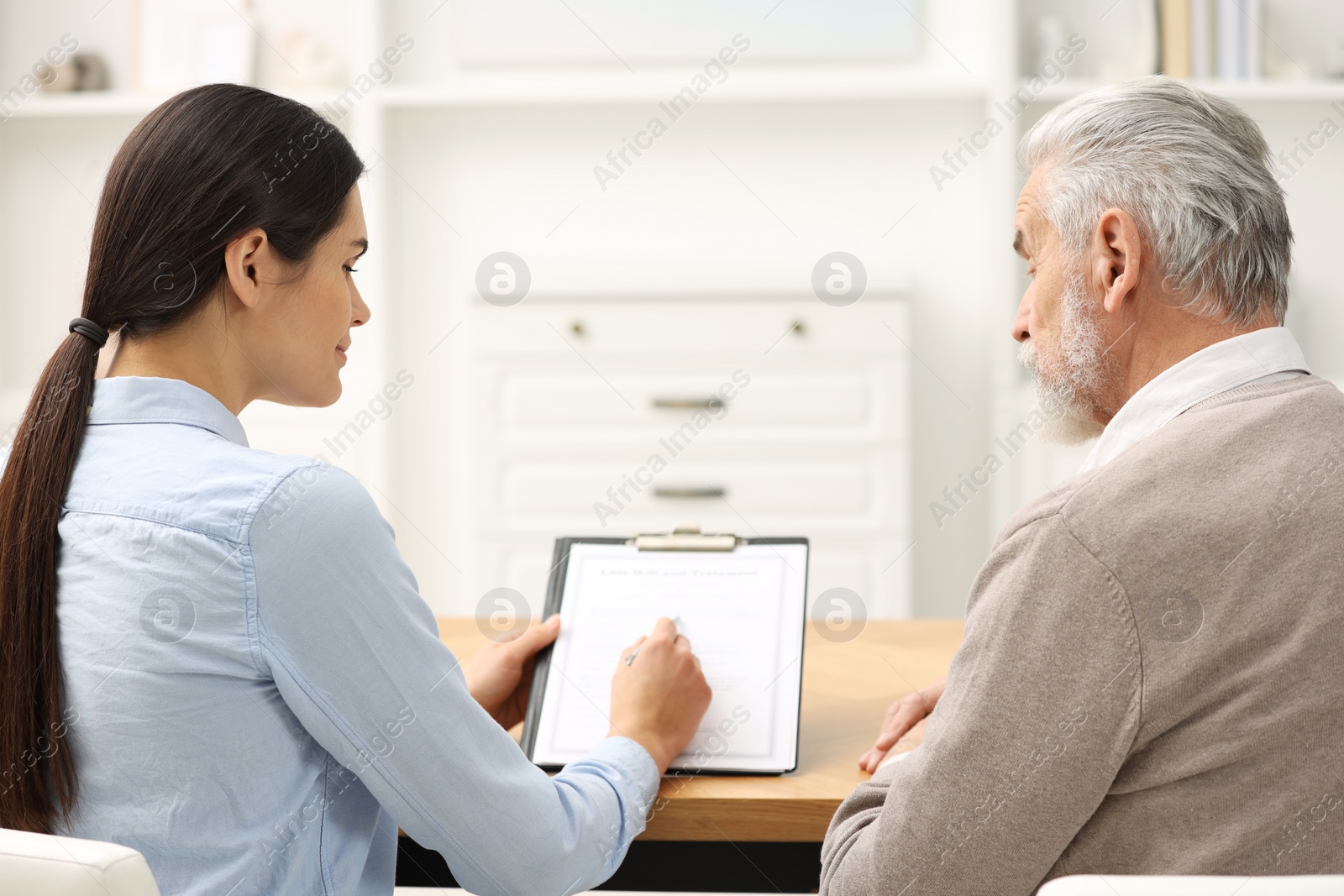 Photo of Notary consulting senior man about Last Will and Testament in office, back view