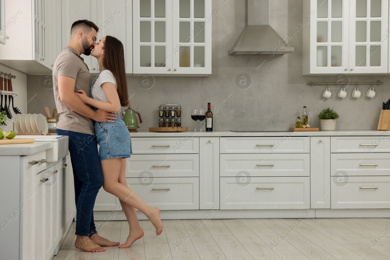 Photo of Affectionate couple kissing in kitchen. Space for text