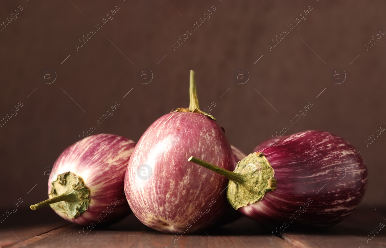 Photo of Ripe purple eggplants on wooden table, closeup