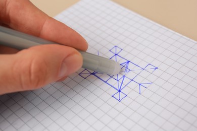 Photo of Woman erasing doodle drawn with erasable pen on sheet of paper against beige background, closeup