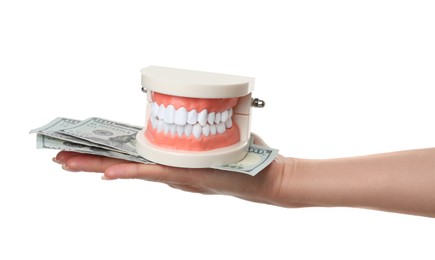 Photo of Woman holding educational dental typodont model and dollar banknotes on white background, closeup. Expensive treatment