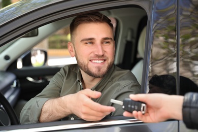 Salesperson giving car key to customer outdoors