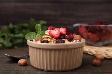Photo of Oatmeal with freeze dried fruits, nuts and mint on wooden table, closeup