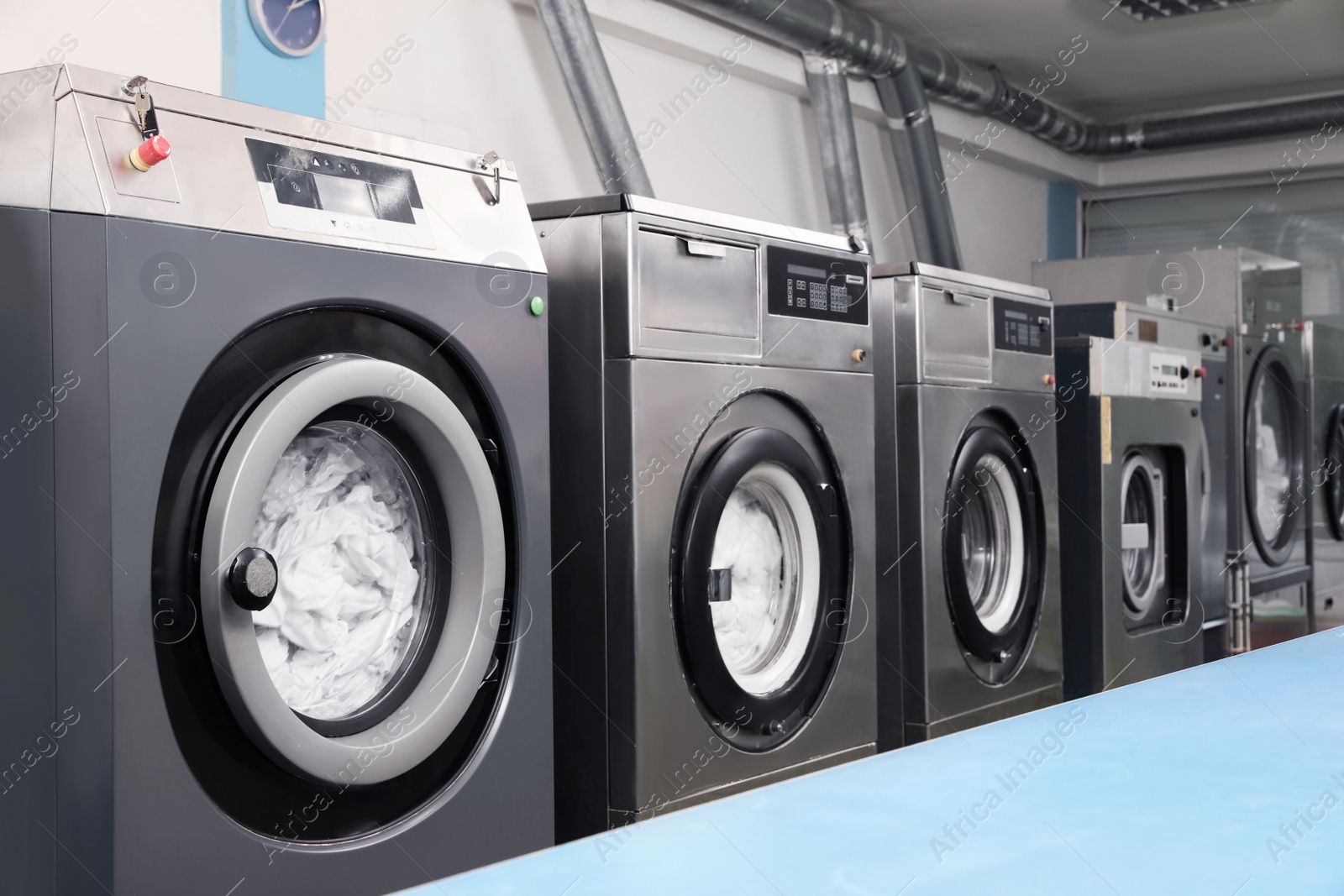 Photo of Row of modern washing machines in dry-cleaning