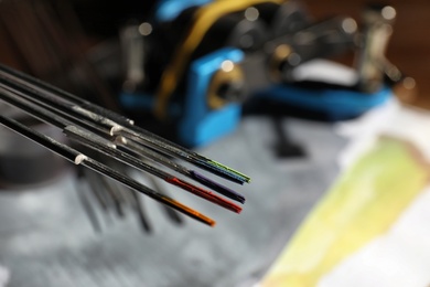 Photo of Tattoo needles with ink on blurred background, closeup