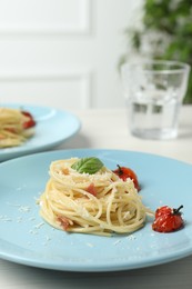 Photo of Tasty spaghetti with tomatoes and cheese served on white wooden table, closeup. Exquisite presentation of pasta dish