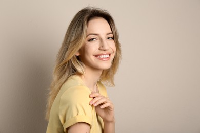 Photo of Portrait of happy young woman with beautiful blonde hair and charming smile on beige background. Space for text