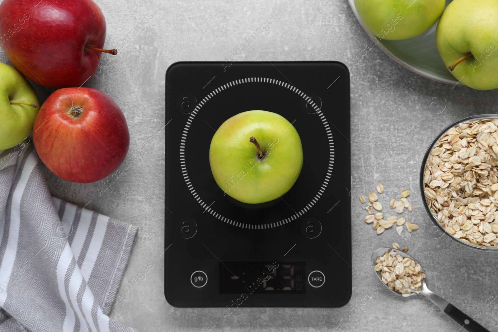 Photo of Digital kitchen scale, apples and oat flakes on grey table, flat lay