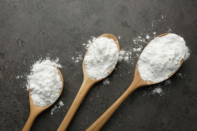 Photo of Baking powder in spoons on grey textured table, flat lay