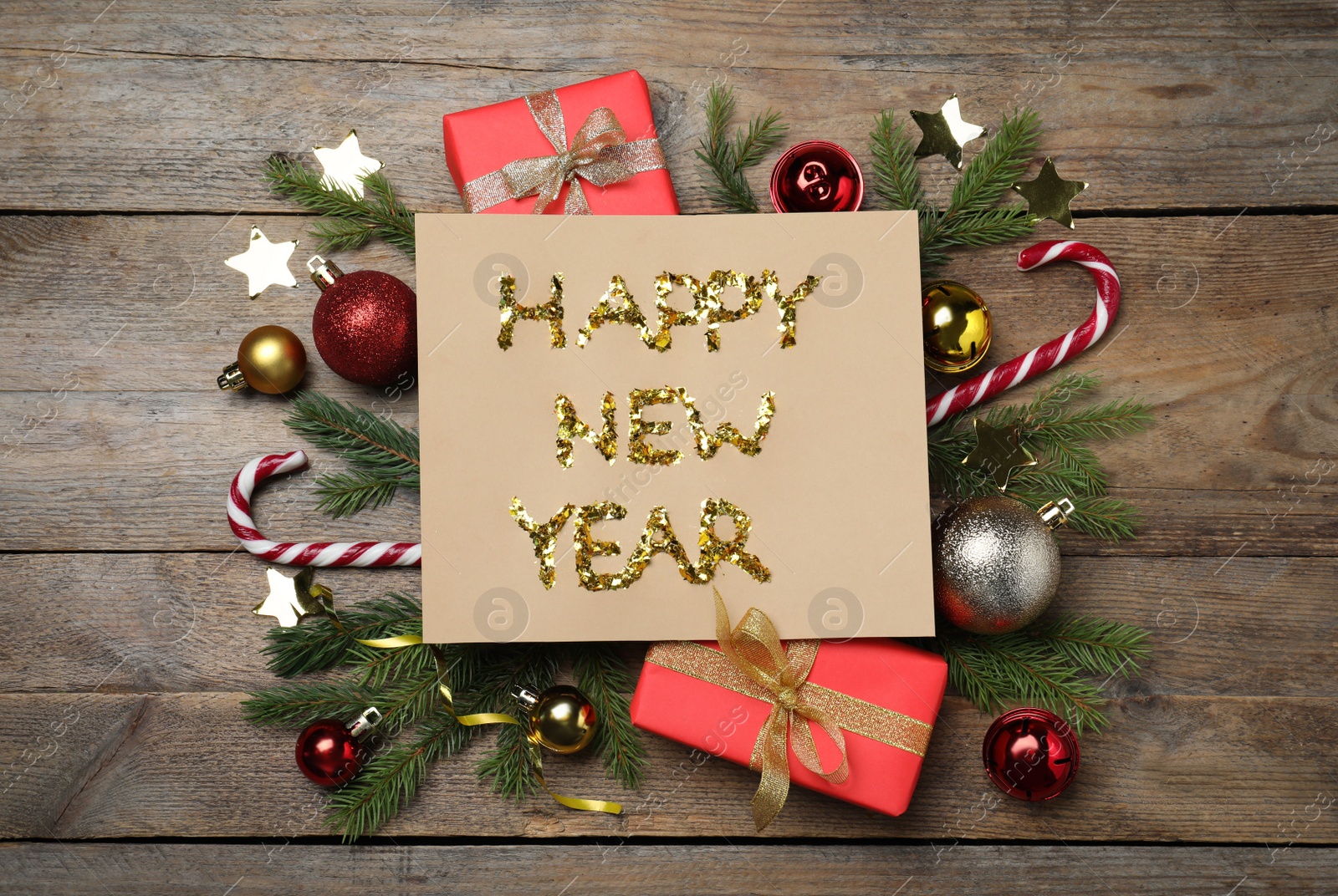 Photo of Card with phrase Happy New Year and festive decor on wooden background, flat lay